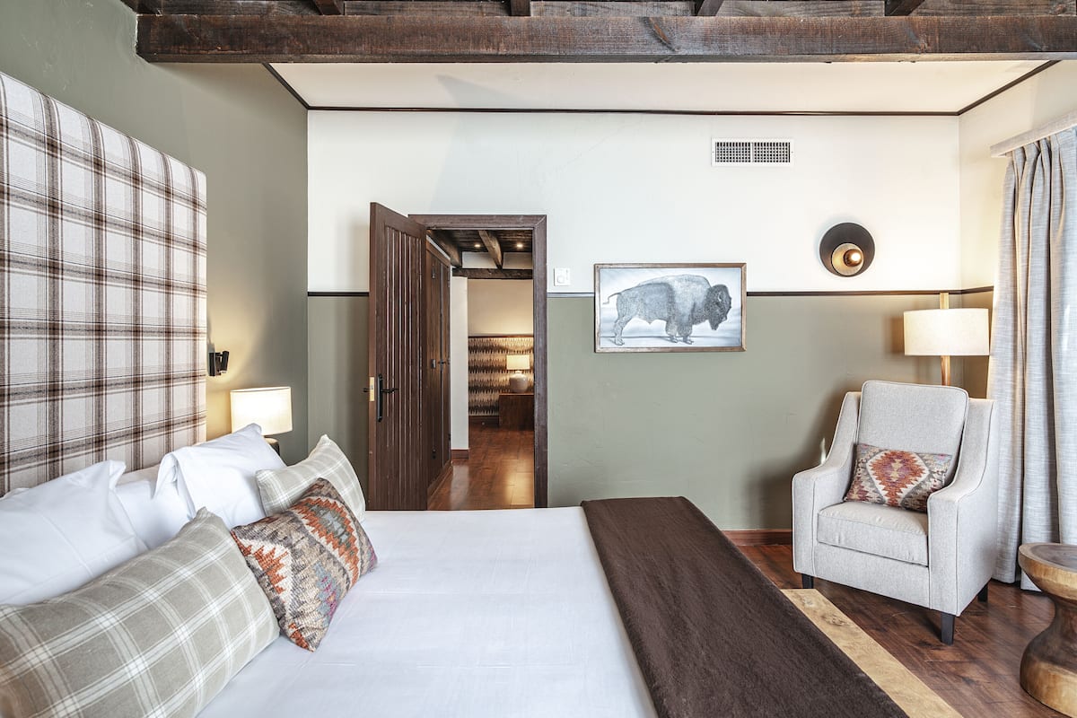 Habitación de hotel con una cama grande, un sofá, una silla y un cuadro en la pared.