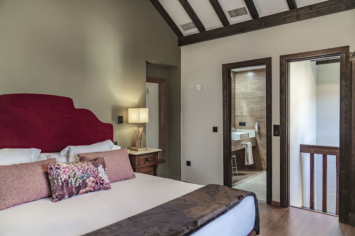 Un dormitorio con una cama grande, una mesita de noche, una lámpara y un cabecero de madera.