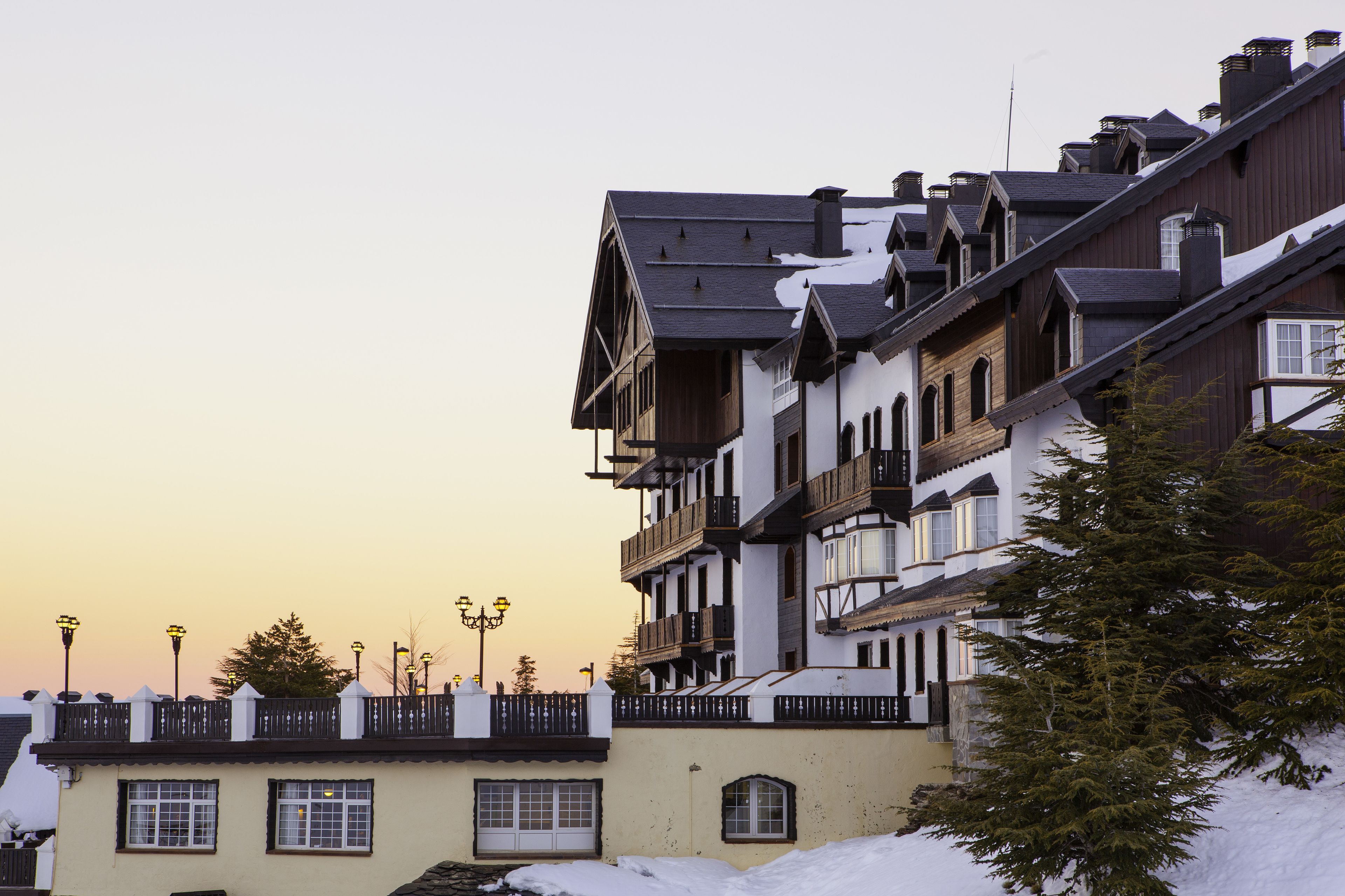 A row of multi-story buildings with balconies, some with snow on the roof, under a clear sky.