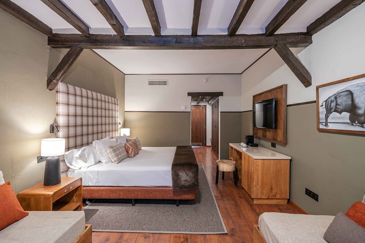 Un dormitorio con cama, mesita de noche, lámpara y espejo.