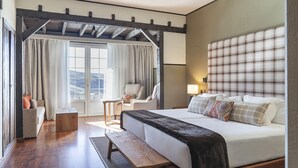 A hotel room with a large bed, a bench, a chair, and a small table. - Hotel Vincci Selección Rumaykiyya (Monachil)
