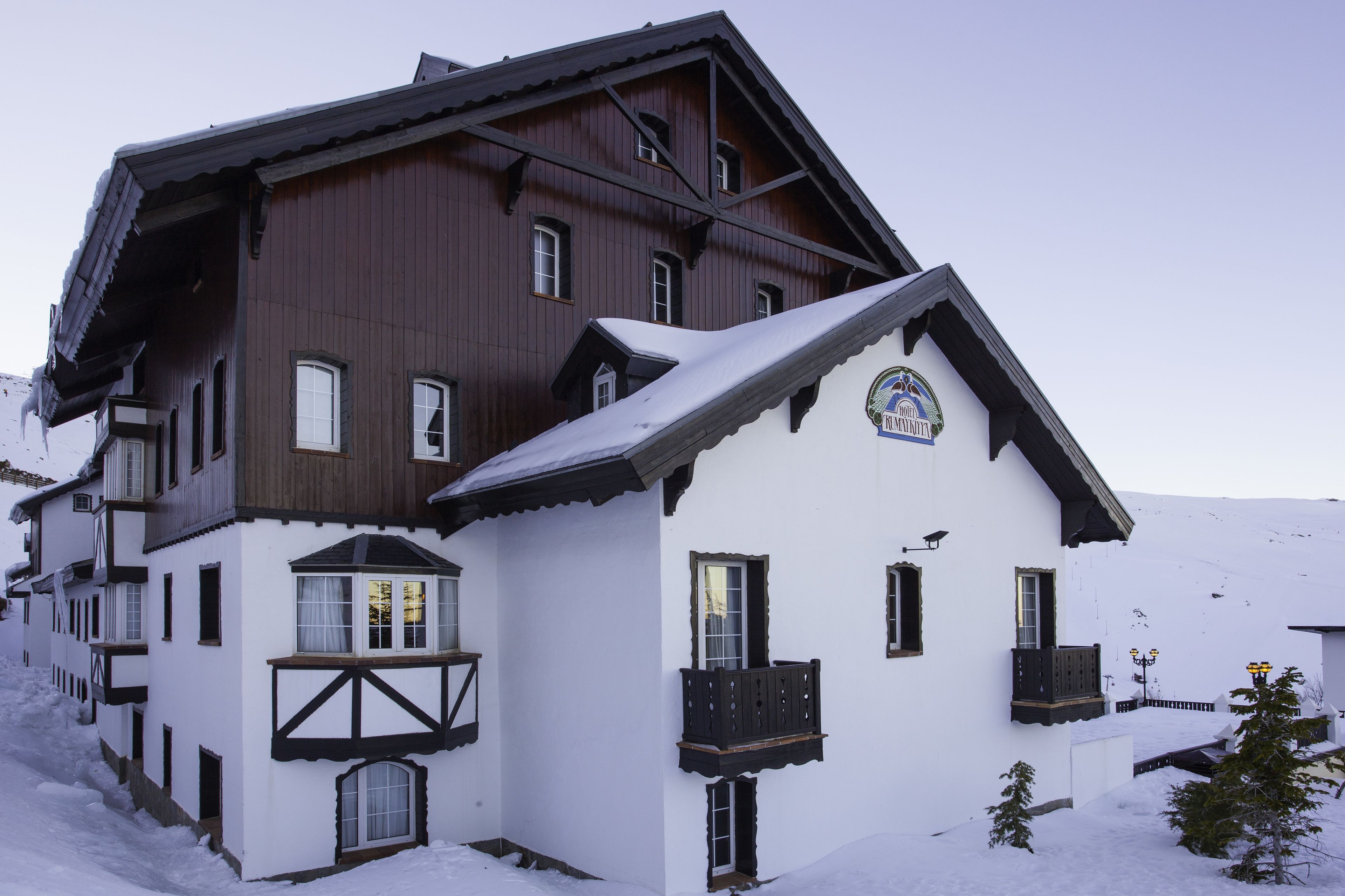 A two-story chalet with a snow-covered roof and a balcony.