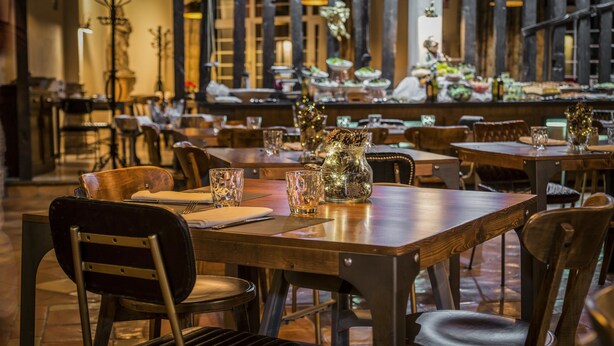 A restaurant interior with wooden tables and chairs, a variety of dishes on the tables, and a warm, dimly lit ambiance. - Hotel Vincci Selección Rumaykiyya (Monachil)