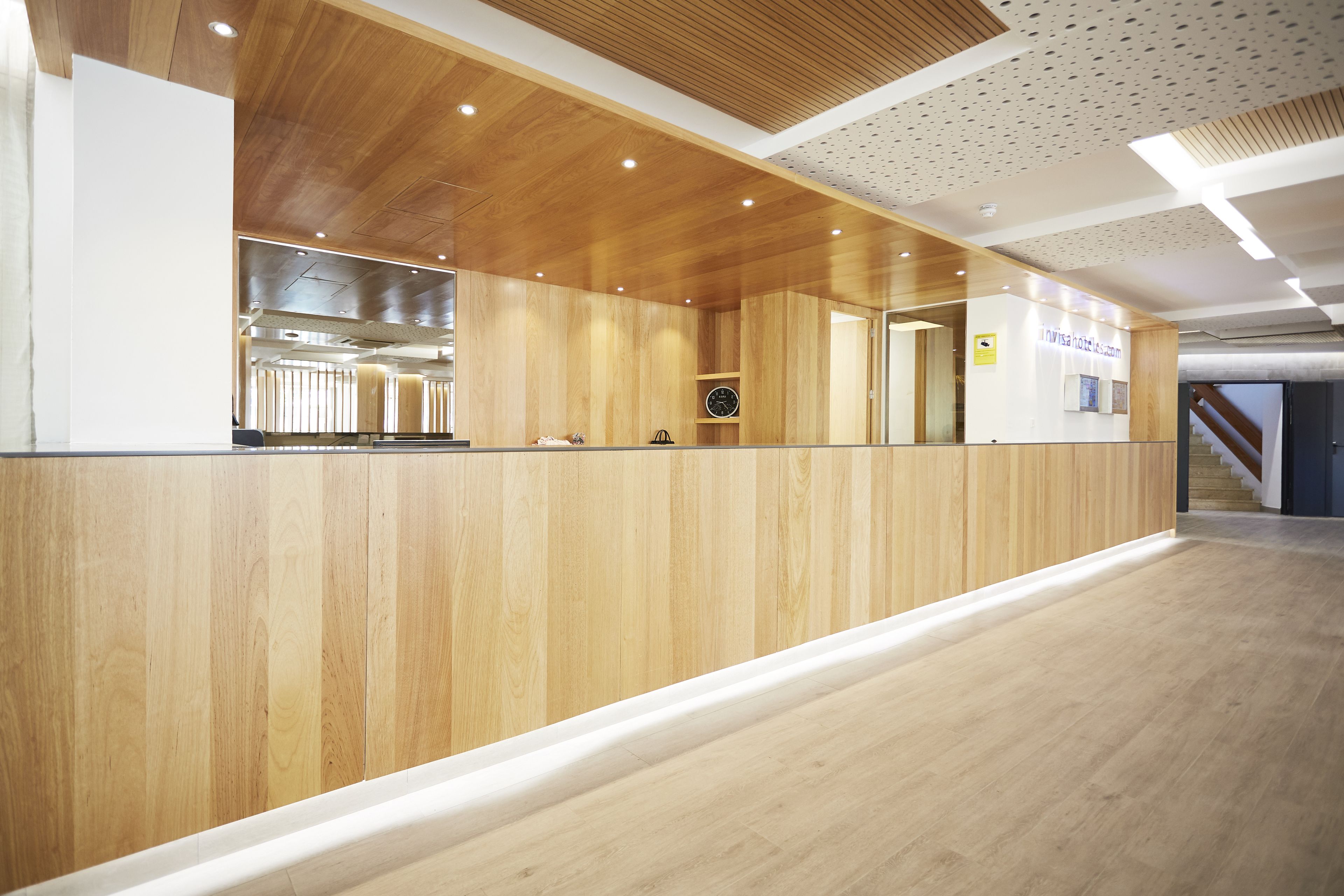 Una zona de recepció amb un taulell de fusta, un rellotge i un rètol de l'Hotel Avis.