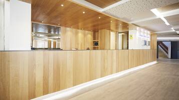 A reception area with a wooden reception desk, a clock, and a sign for the Avis Hotel.