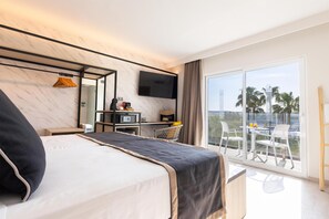 A hotel room with a large bed, a desk with a computer, a flat-screen TV, and a balcony with outdoor seating. - Invisa Hotel Es Pla - Adults Only (Sant Antoni de Portmany)