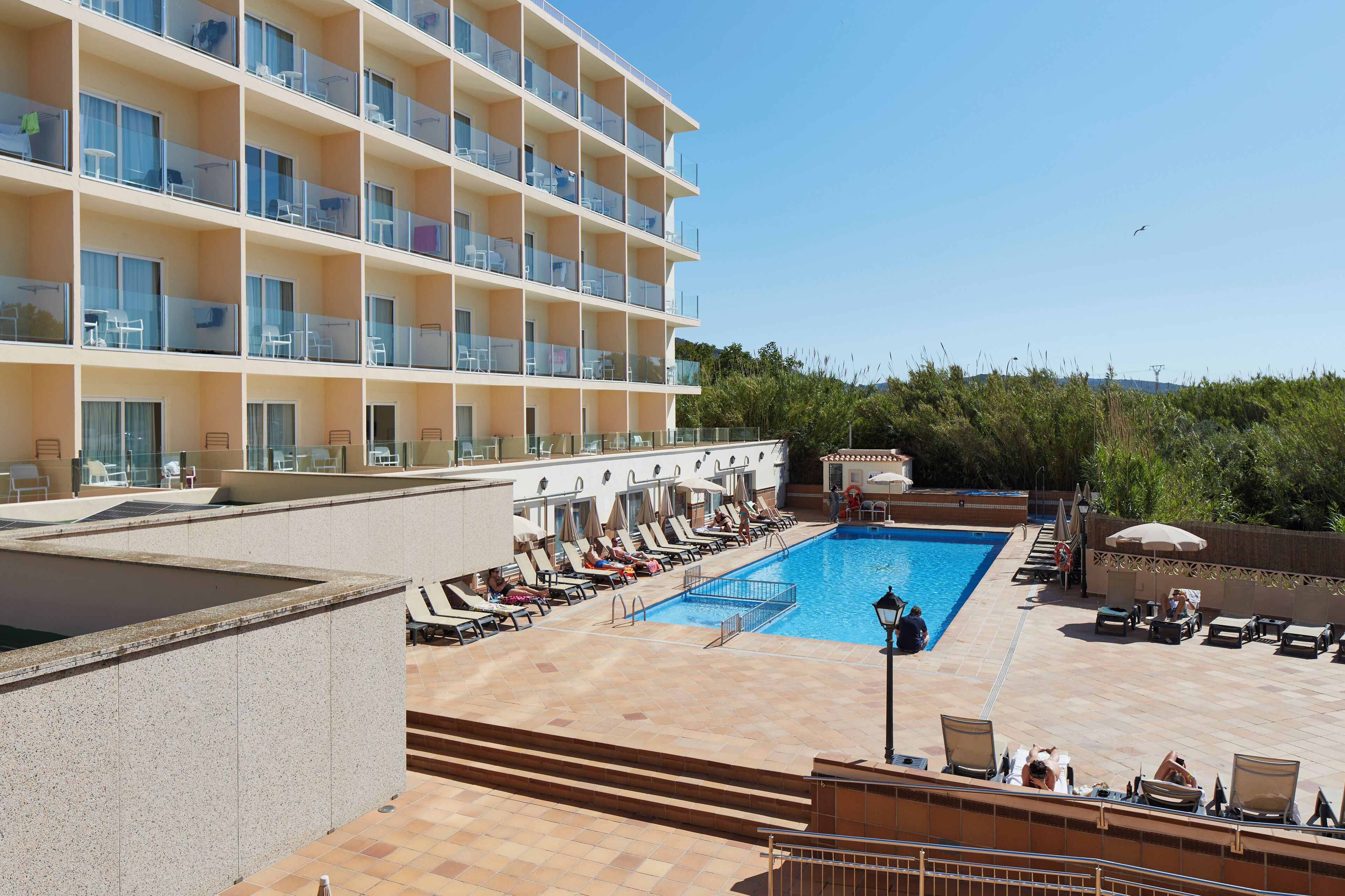 A hotel with a pool area, multiple balconies, and outdoor seating.