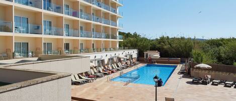 A hotel with a pool area, multiple balconies, and outdoor seating.