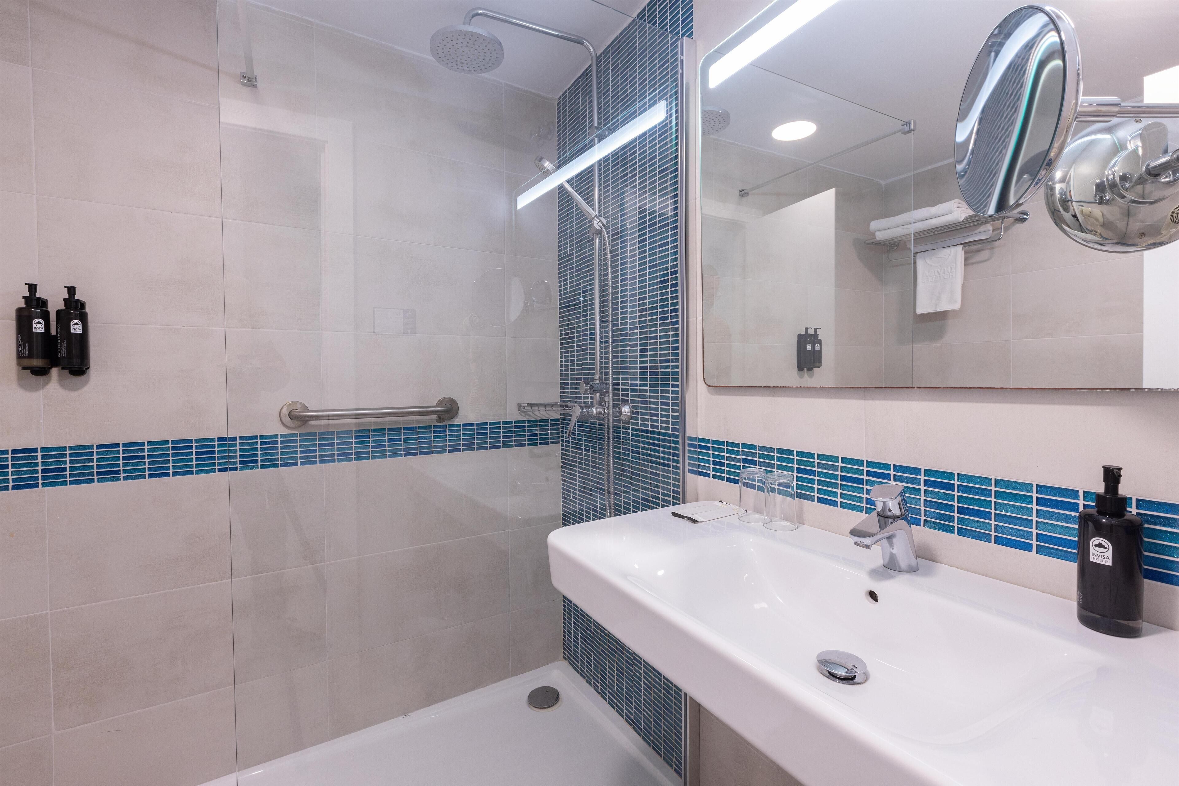 A modern bathroom with a shower, a sink, and a mirror.
