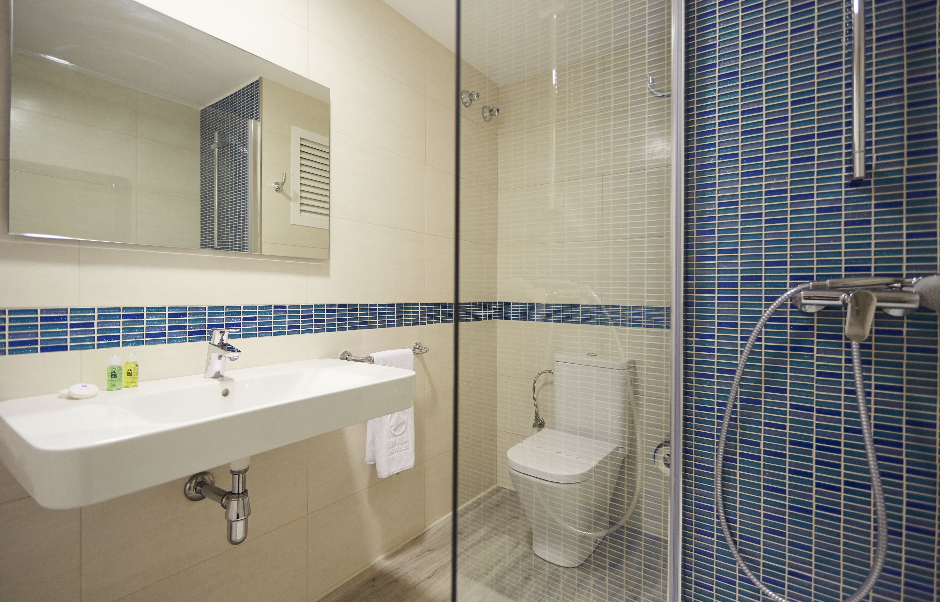 A bathroom with a glass-enclosed shower, a sink with a mirror, and a toilet.