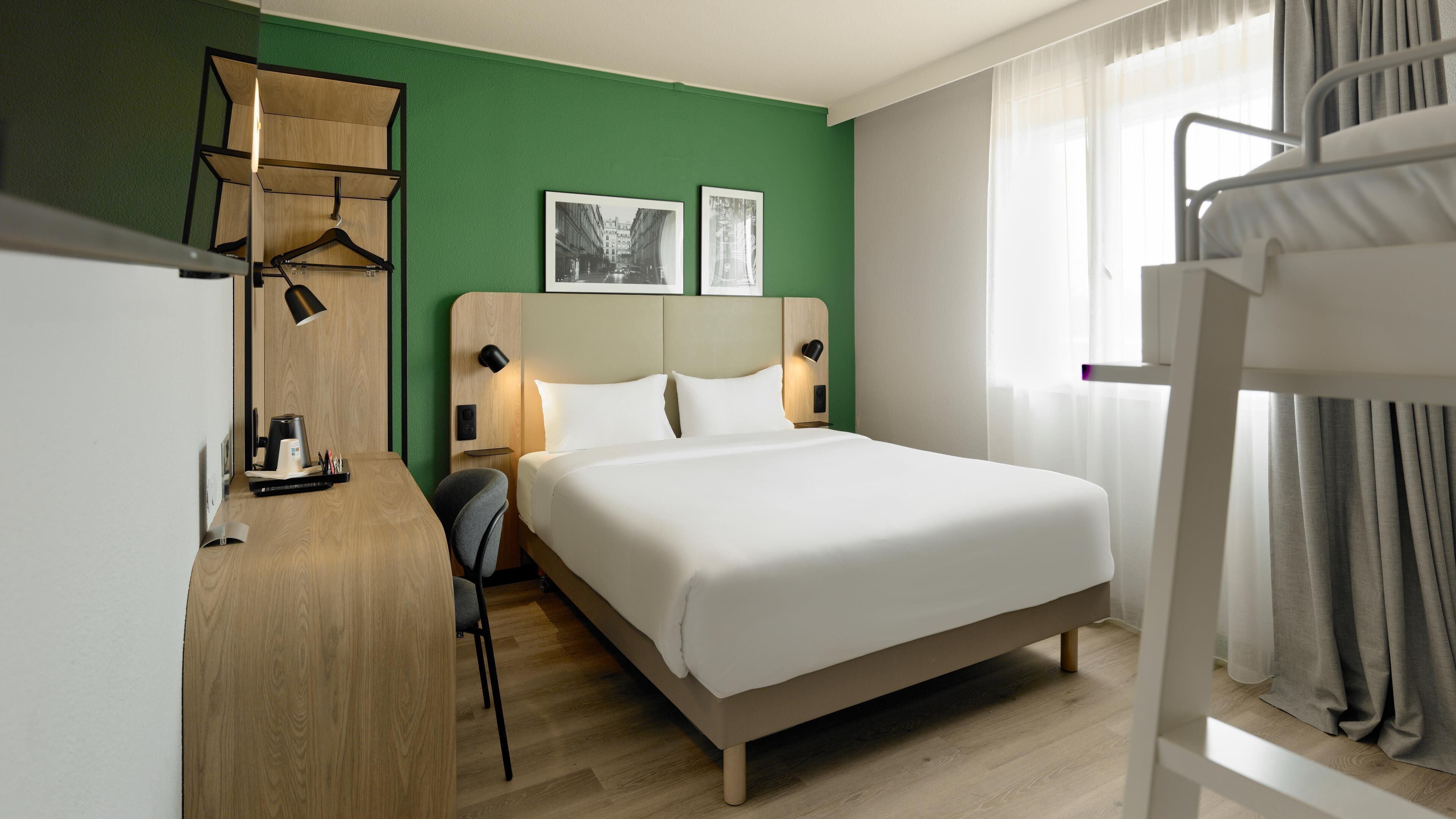 Ett hotellrum med en säng, ett skrivbord, en stol och en våningssäng.