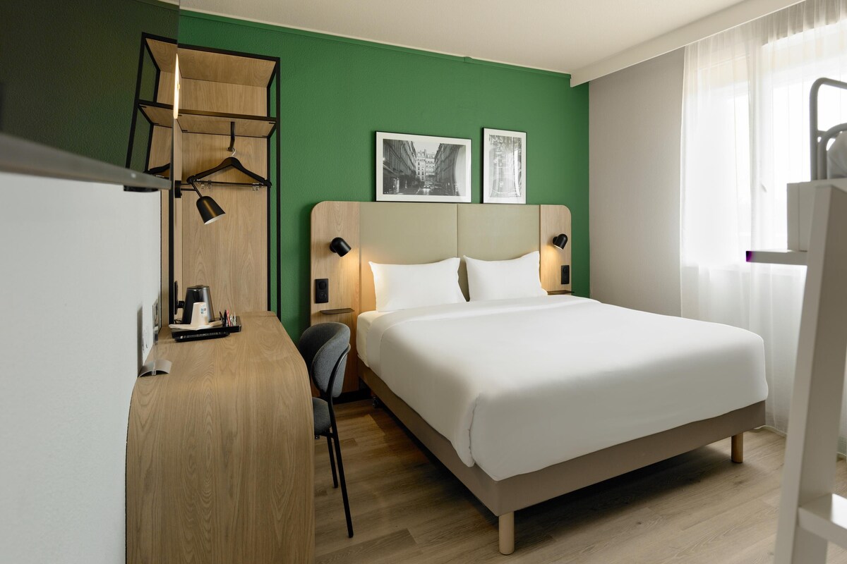 Una camera d'albergo con un letto, una scrivania, una sedia e un letto a castello.