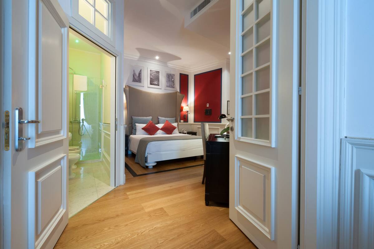 Una habitación de hotel con cama, mesita de noche y vistas al baño.