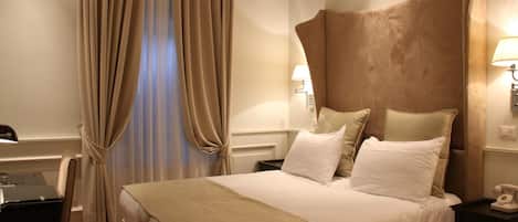 Una habitación de hotel con una cama grande, cortinas color beige, un escritorio y una lámpara.