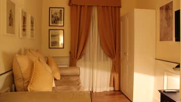 A room with a sofa, curtains, framed pictures on the wall, and a door.