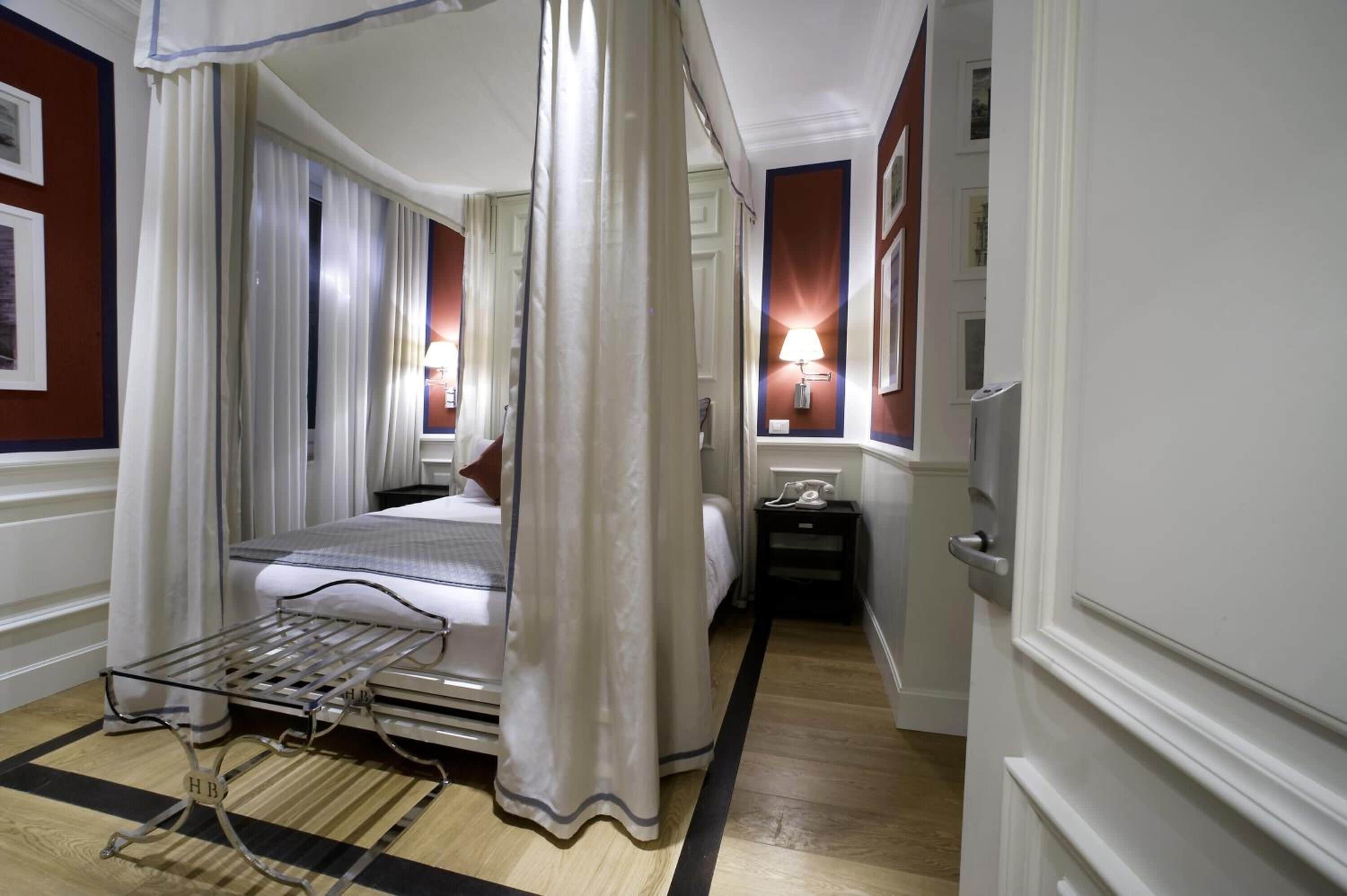 Une chambre d’hôtel avec un lit, une table de chevet, une lampe et une fenêtre avec des rideaux.