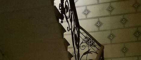 A staircase with ornate black metal railings and a wooden handrail.
