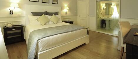 A hotel room with a large bed, bedside tables, a desk, and a chair.