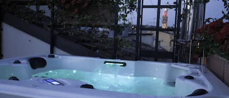 A hot tub with a waterfall feature, surrounded by greenery and a staircase.