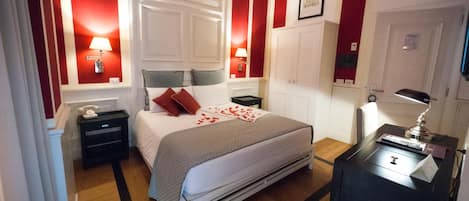 Une chambre d’hôtel comprenant un lit, des tables de chevet, un bureau avec une lampe et une armoire.