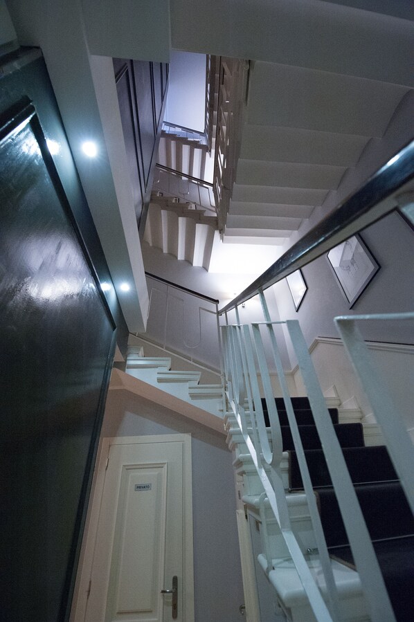 Un escalier avec des rampes blanches menant à un palier où se trouve une porte portant l’inscription « PRIVÉ ».