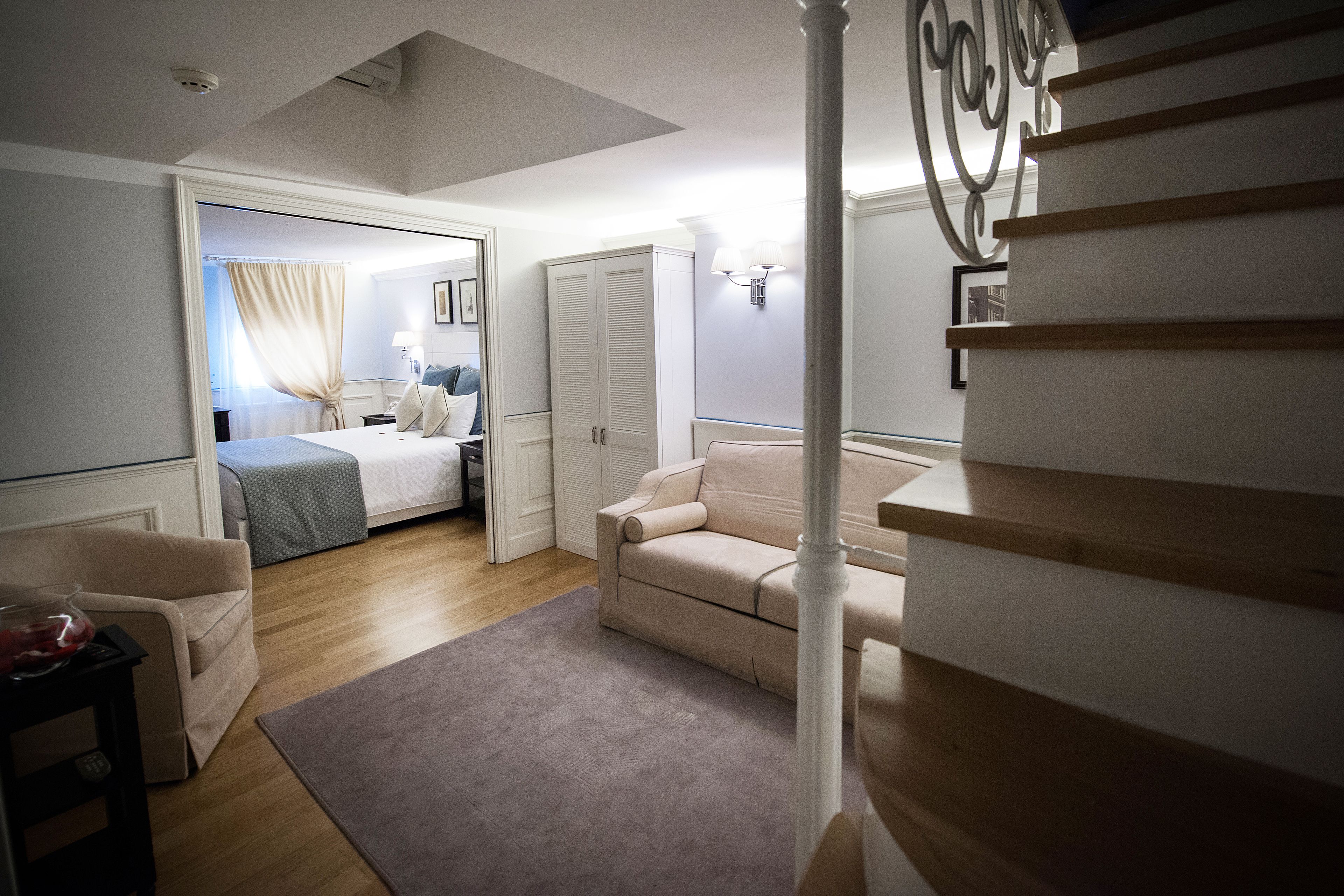 A bedroom with a bed, a chair, a desk, and a staircase.