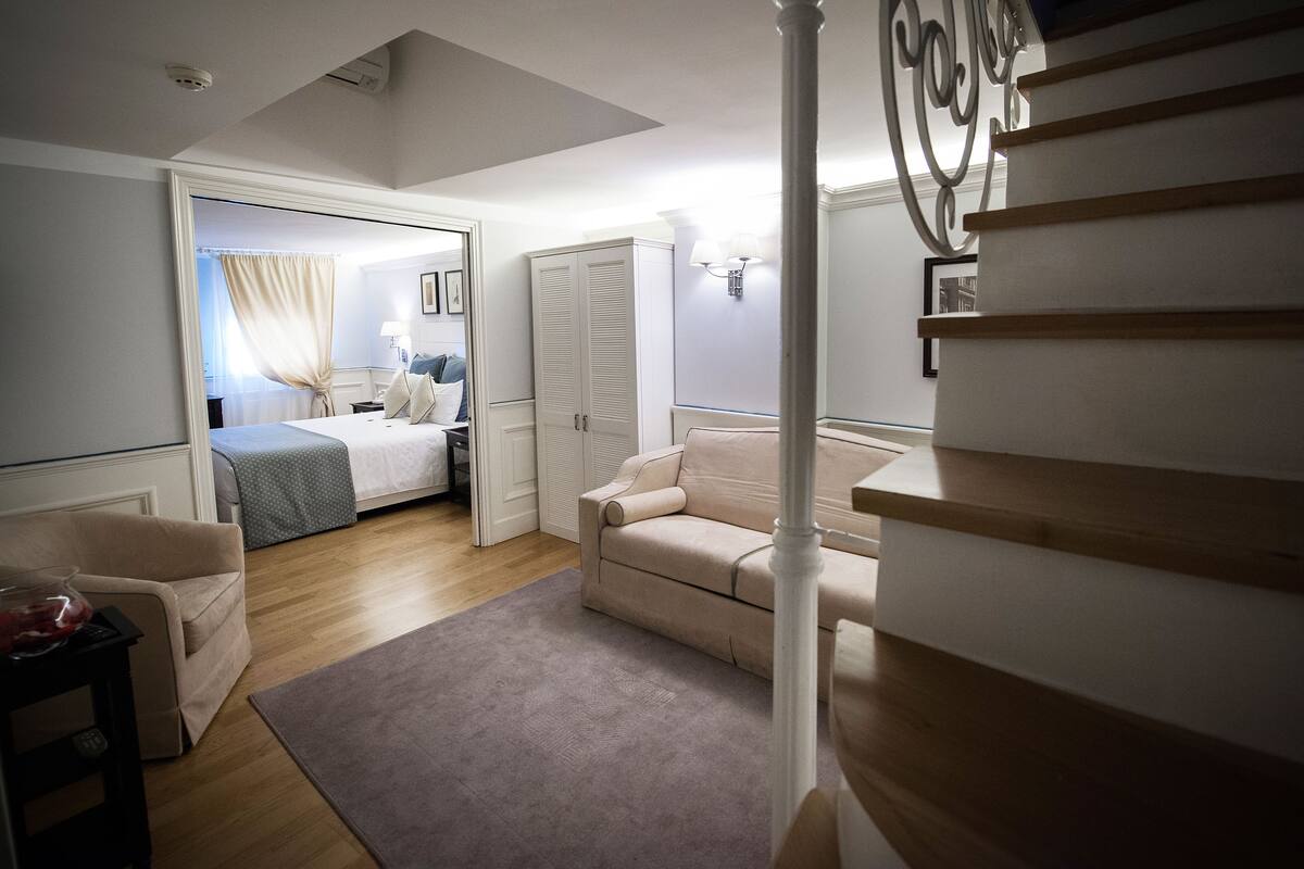 Un dormitorio con una cama, una silla, un escritorio y una escalera.