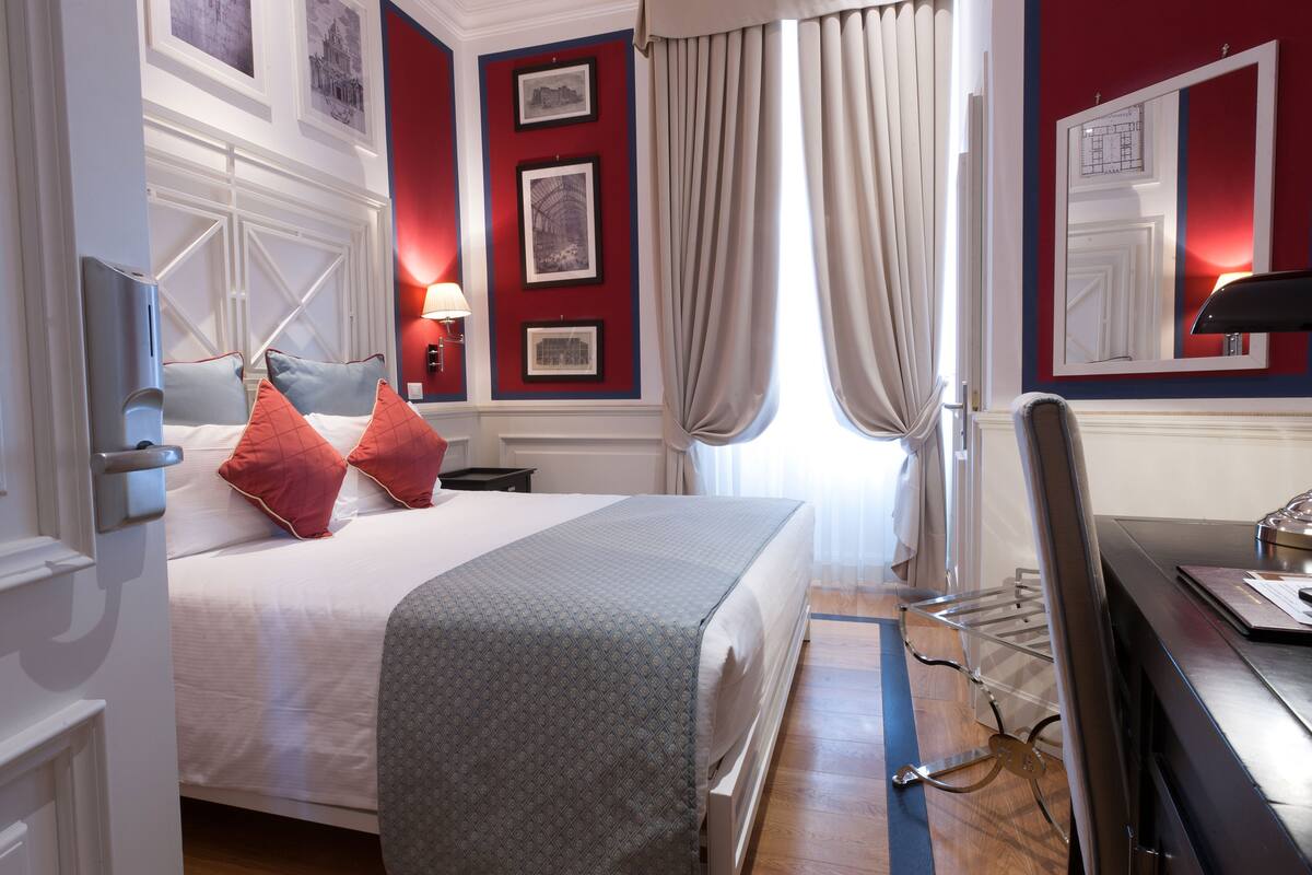 A hotel room with a bed, a desk, and a chair.