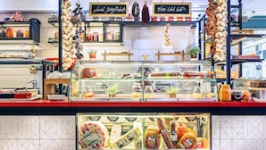 A deli counter with glass display cases filled with various cheeses, meats, and other deli items. - Airotel Alexandros Hotel (Athens)
