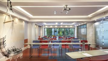 A conference room with tables and chairs, a projector, and a hanging hammock.