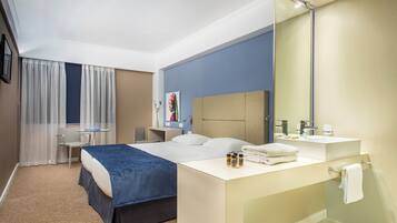 A hotel room with a bed, bedside table, and a large mirror.