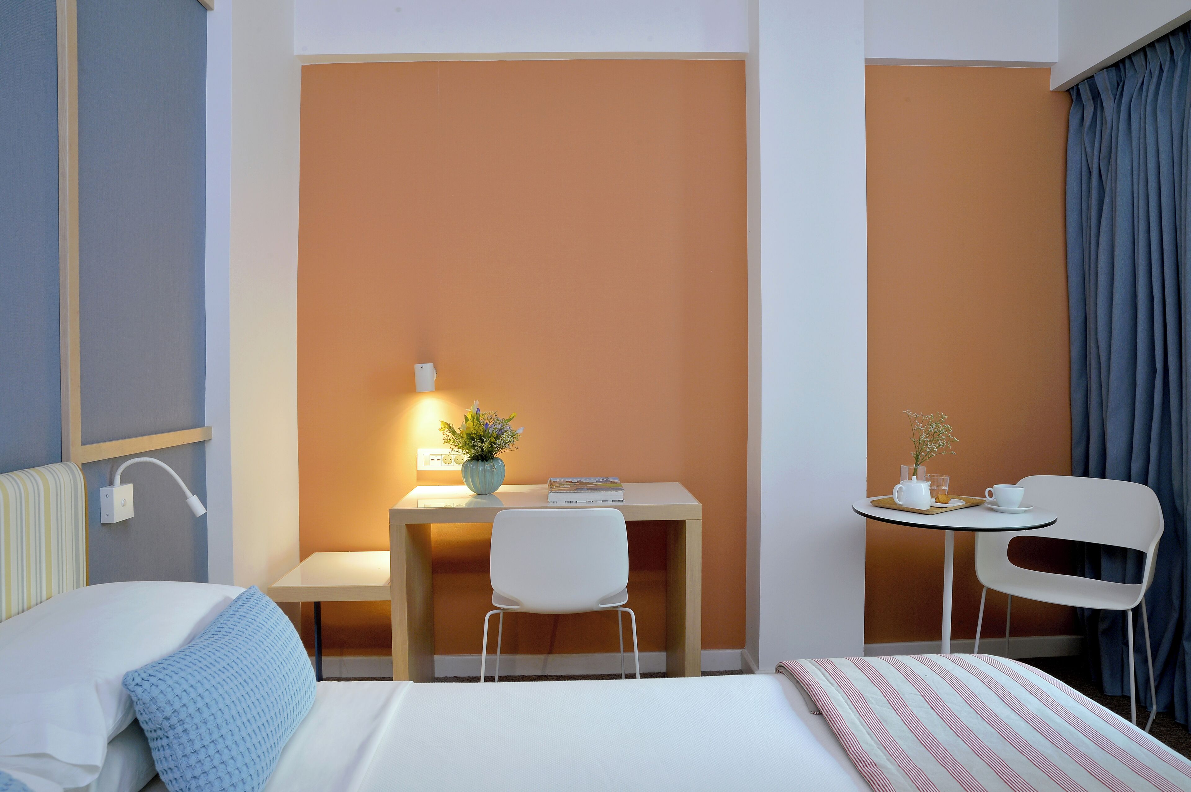 Una camera d'albergo con un letto, una scrivania, una sedia e un tavolino con una tazza e un piattino.