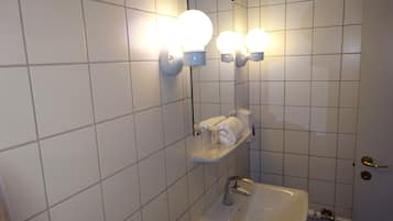A bathroom with a white sink, a mirror, and wall-mounted lights.