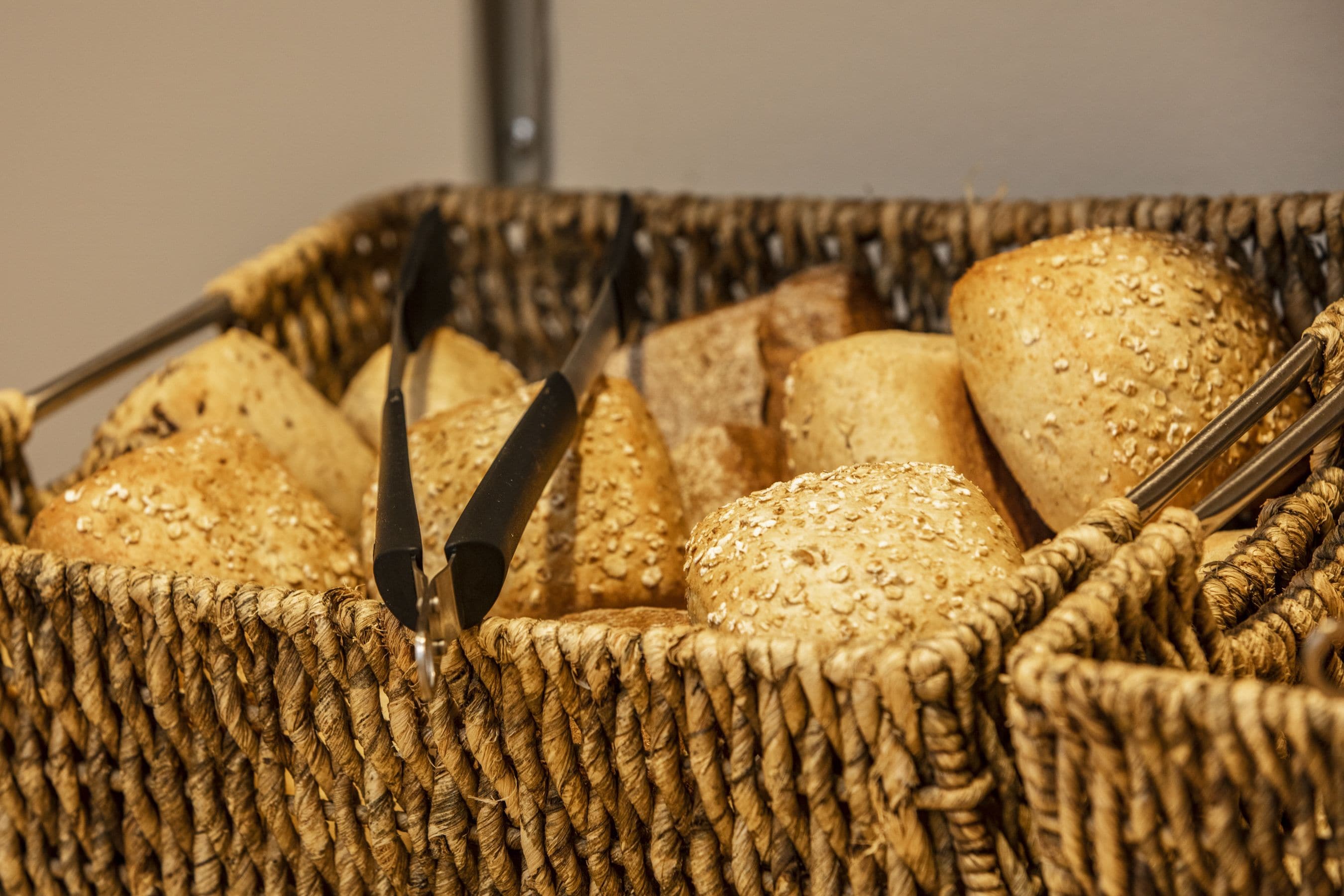 Un cesto pieno di diversi tipi di pane, tra cui pagnotte con semi e una baguette.