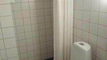 Un baño pequeño con inodoro, cortina de ducha y dispensador de papel higiénico.