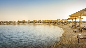 A beach with rows of sun loungers and umbrellas, a pebble beach, and a calm sea. - Laguna Maradiso Hotel by Aminess  (Novigrad)
