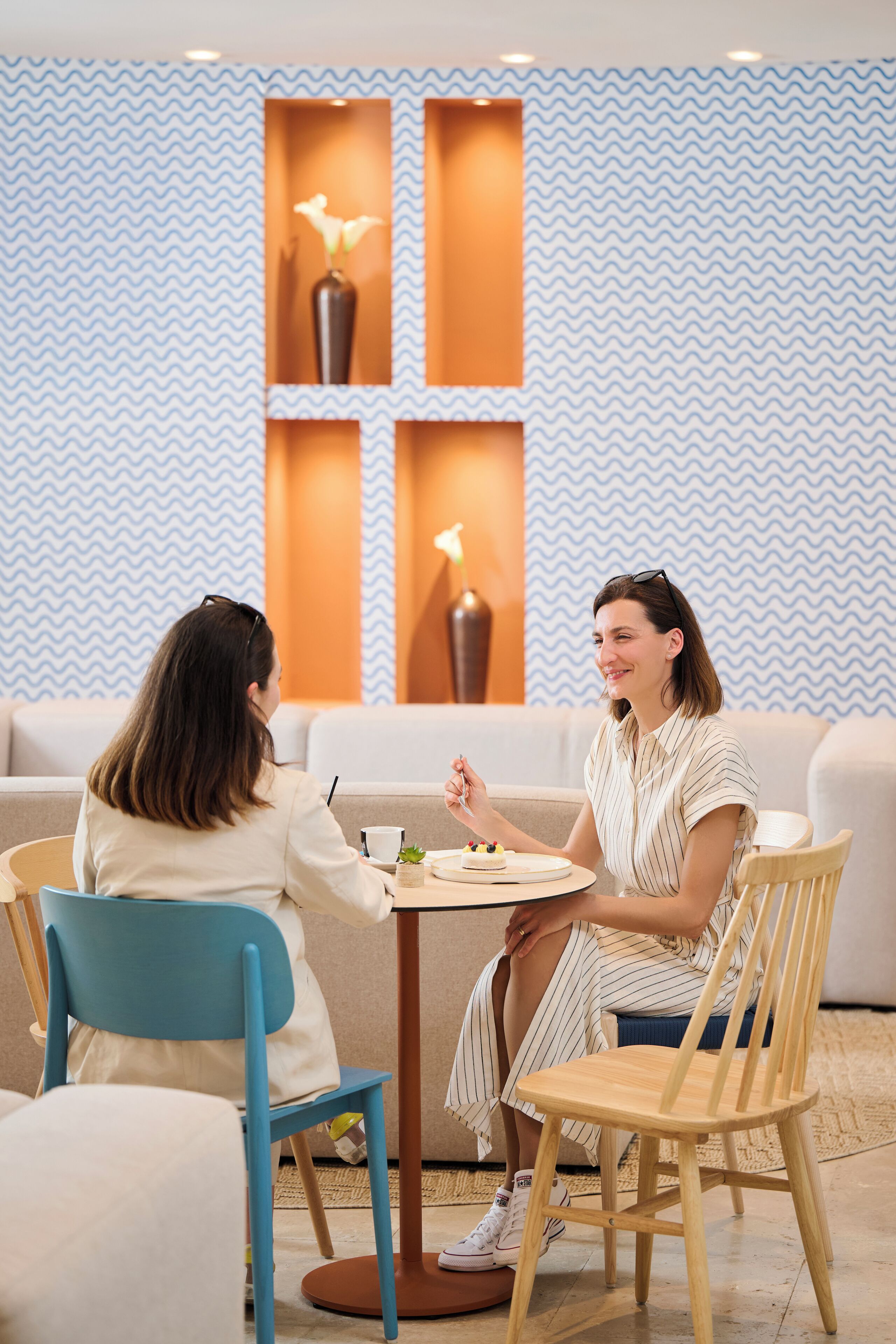 Un interior moderno con una pared estampada, un sofá, una mesa de comedor y dos sillas.