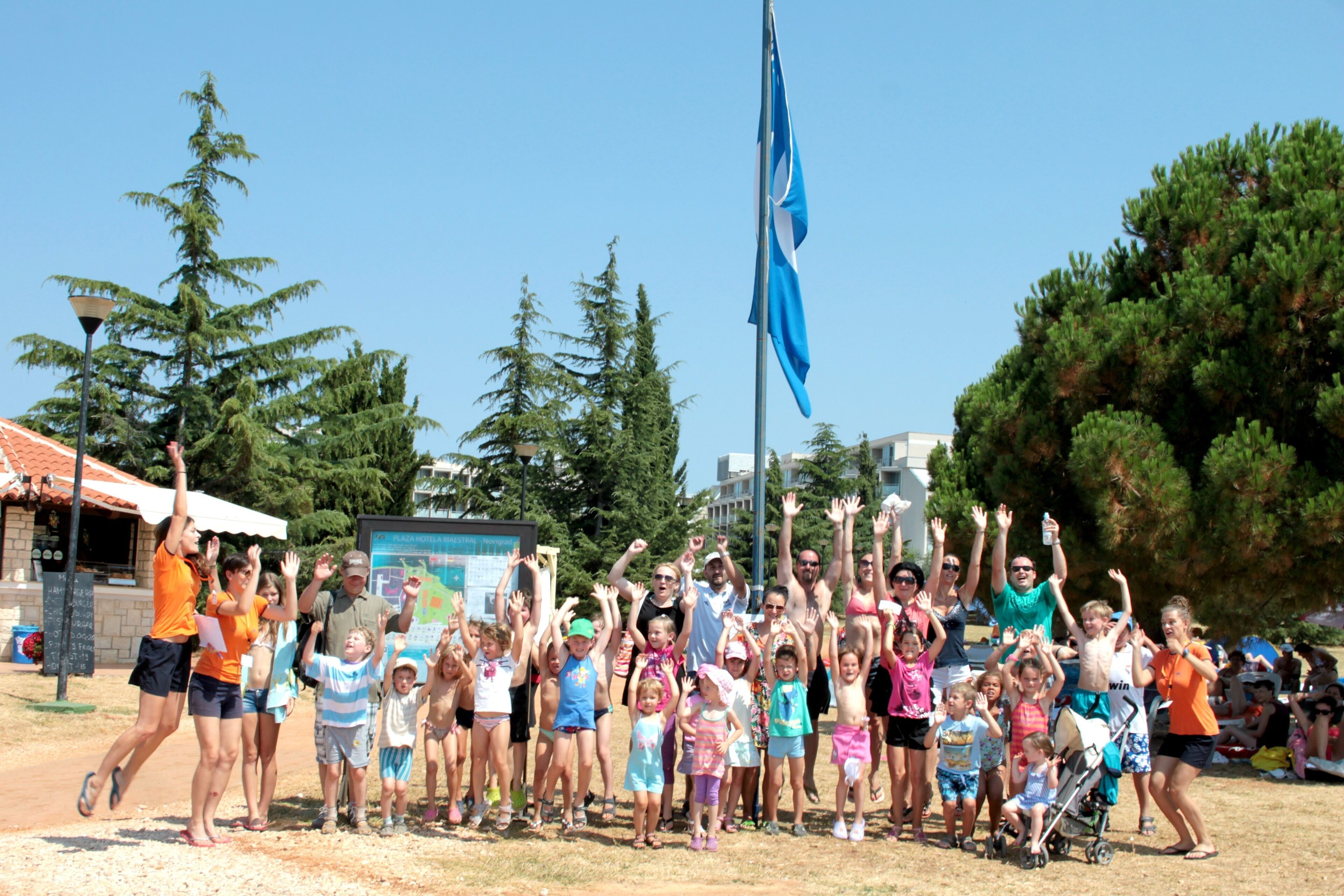 A group of people posing for a photo in an outdoor setting with trees and a building in the background.