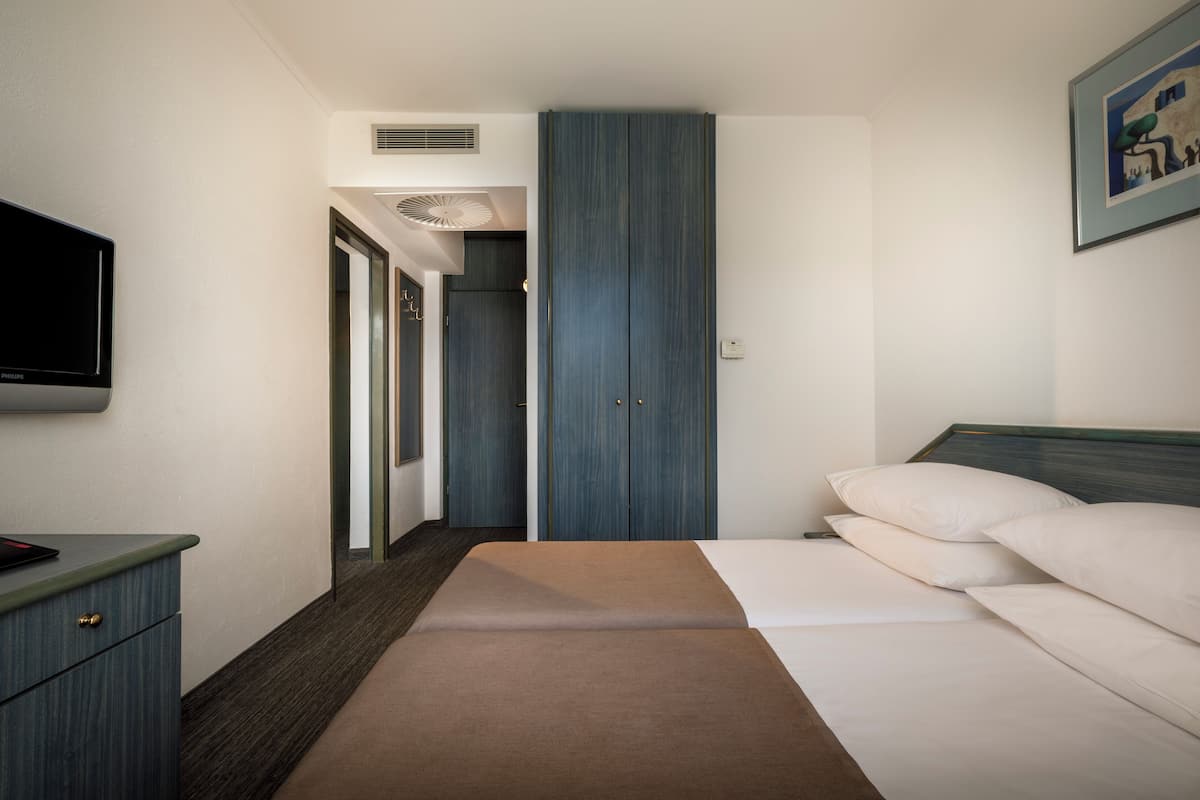 Una habitación de hotel con cama, televisión, escritorio y armario.