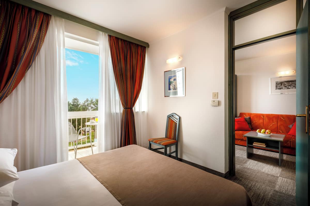Habitación de hotel con cama, una silla, un sofá y un balcón con mesa.