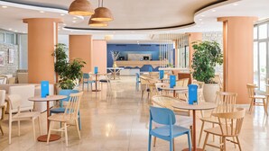 A modern hotel lobby with round tables and chairs, a reception desk, and potted plants. - Laguna Maradiso Hotel by Aminess  (Novigrad)