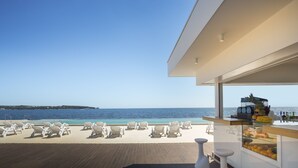 A beachside lounge with white lounge chairs and a bar area with fruit and beverages.