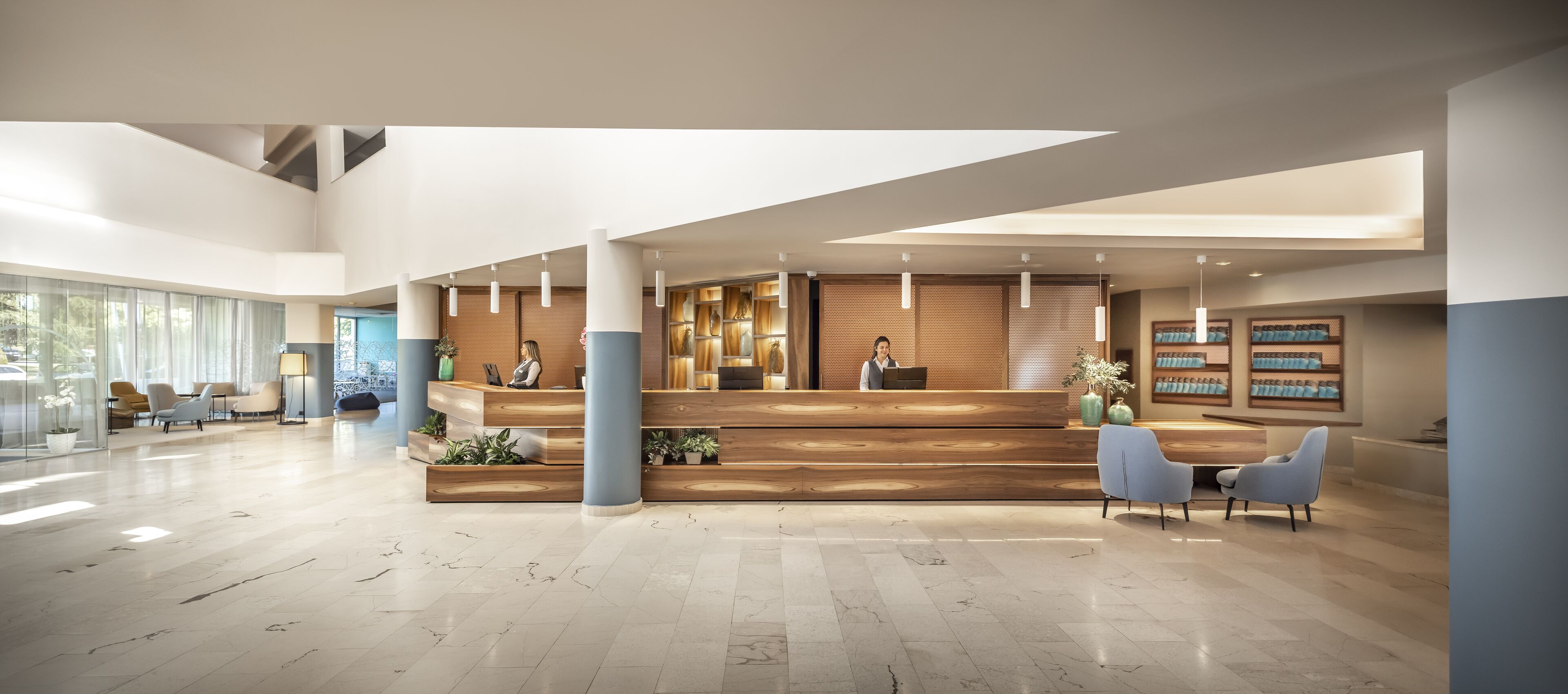 Eine geräumige Lobby mit einer Rezeption, Sitzgelegenheiten und großen Fenstern.