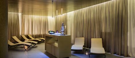 A spa area with a reception desk, lounge chairs, and a massage chair.