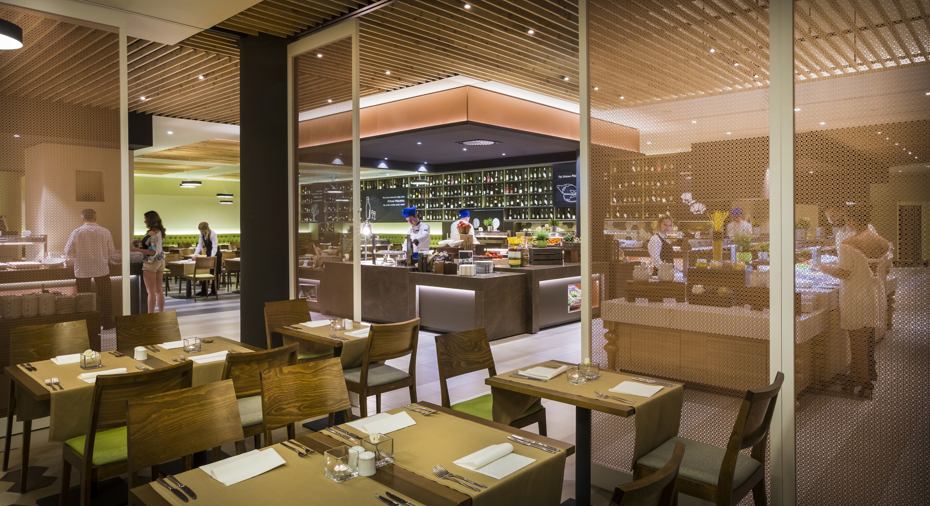 A restaurant with wooden furniture, a bar area, and a view of the dining area through a glass partition.