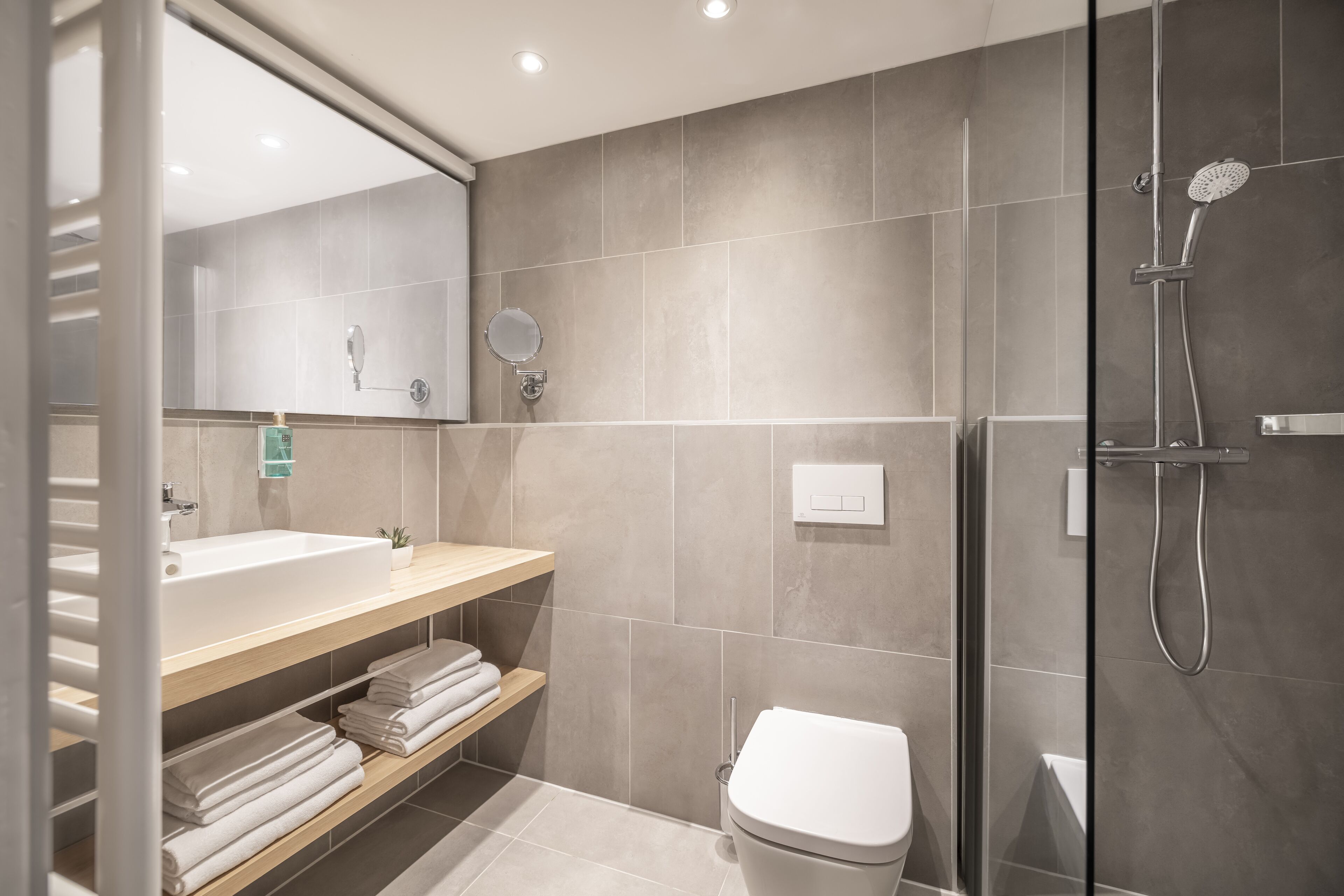 A modern bathroom with a large sink, a toilet, and a shower area.