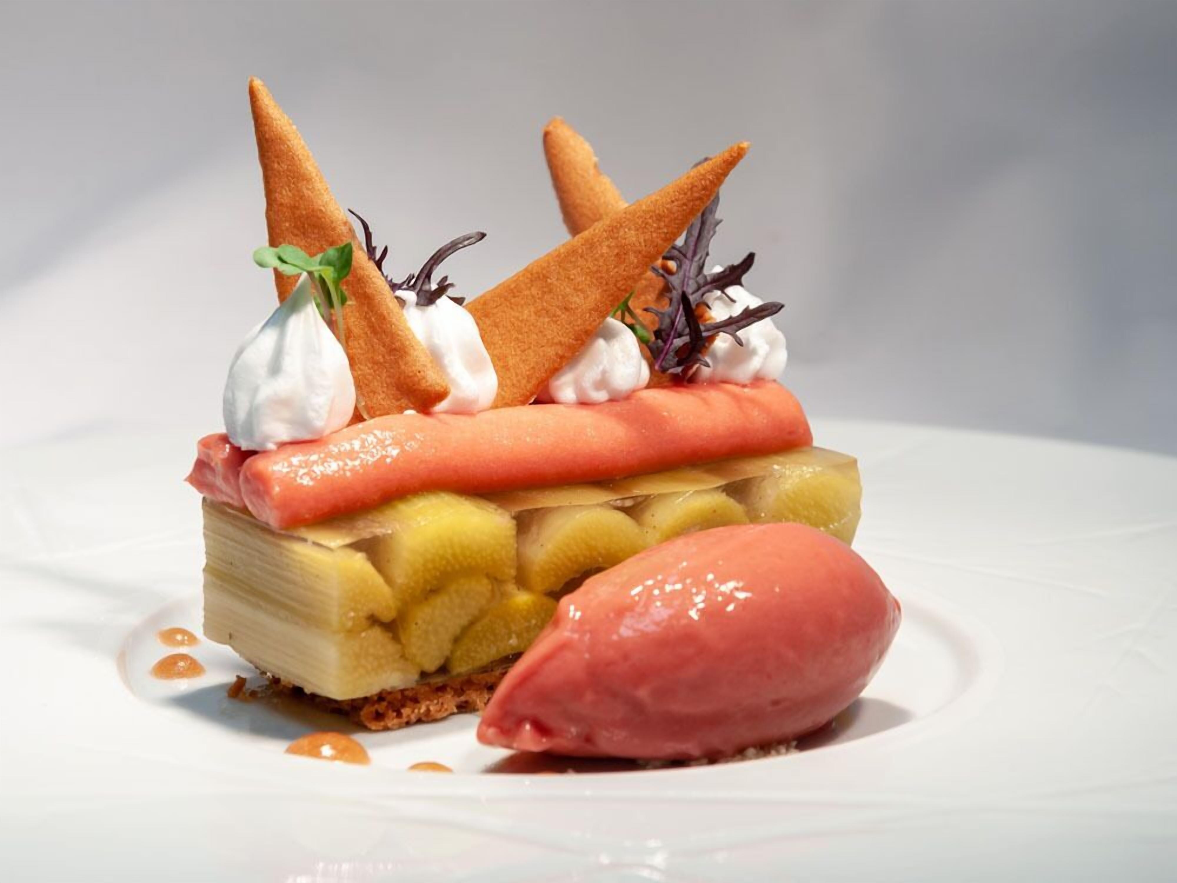 A dessert with a layered cake, fruit, and a scoop of ice cream.