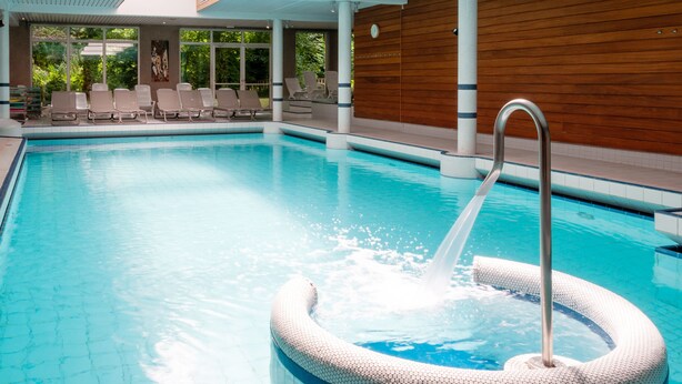 A swimming pool with a hexagonal hot tub, lounge chairs, and wooden paneling. - Hotel Restaurant & Spa Verte Vallée (Munster)