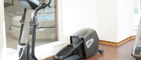 A stationary bike in a room with a wooden floor and a window.