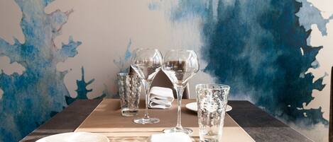 A table set with a folded white napkin, a fork, a knife, and several wine glasses and water glasses.